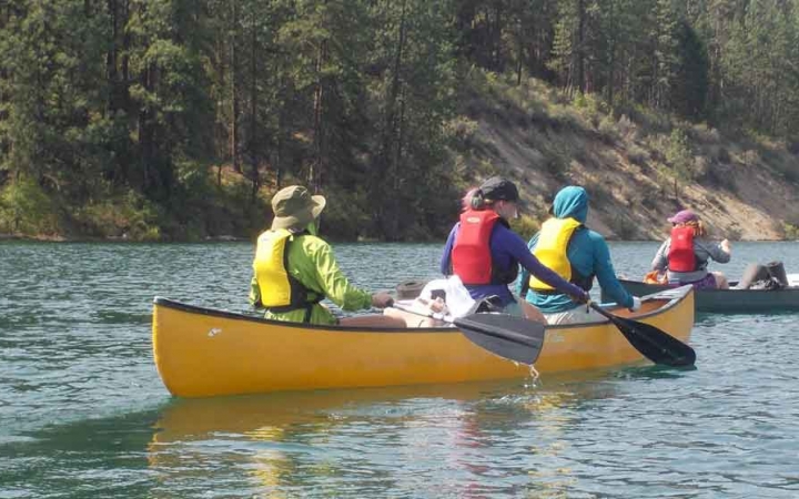 a group of students paddle canoes on a lake in washington state